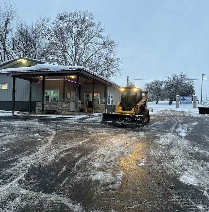 bobcat machine clearing a snowy parking lot