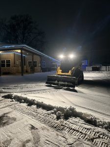 snowplow clearing a parking lot at night